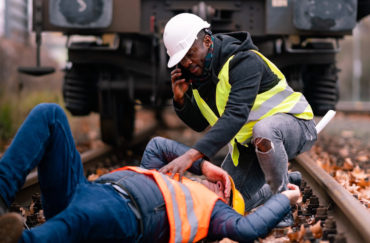 worker injured in an accident at work on the railway tracks. Coworker calling for help